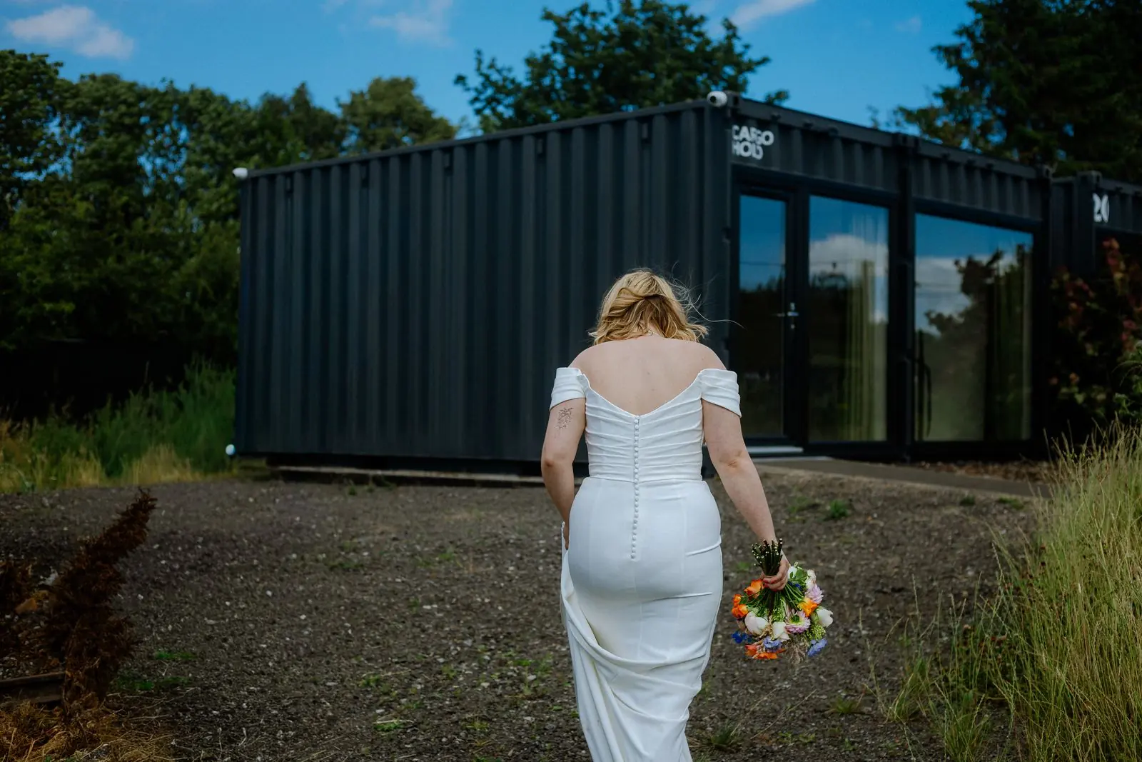Bride walking away holding a bright bouquet