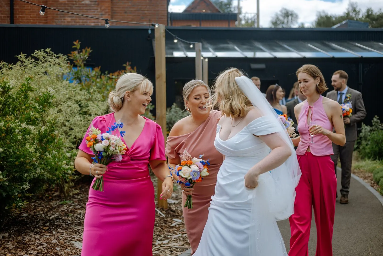 Bride laughing with bridesmaids in pink outside
