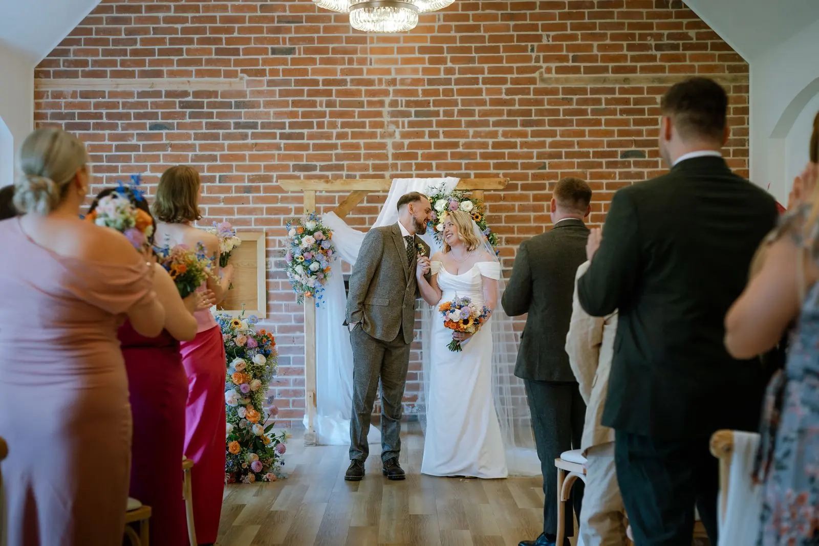 Ceremony in front of a brick wall with bright flowers
