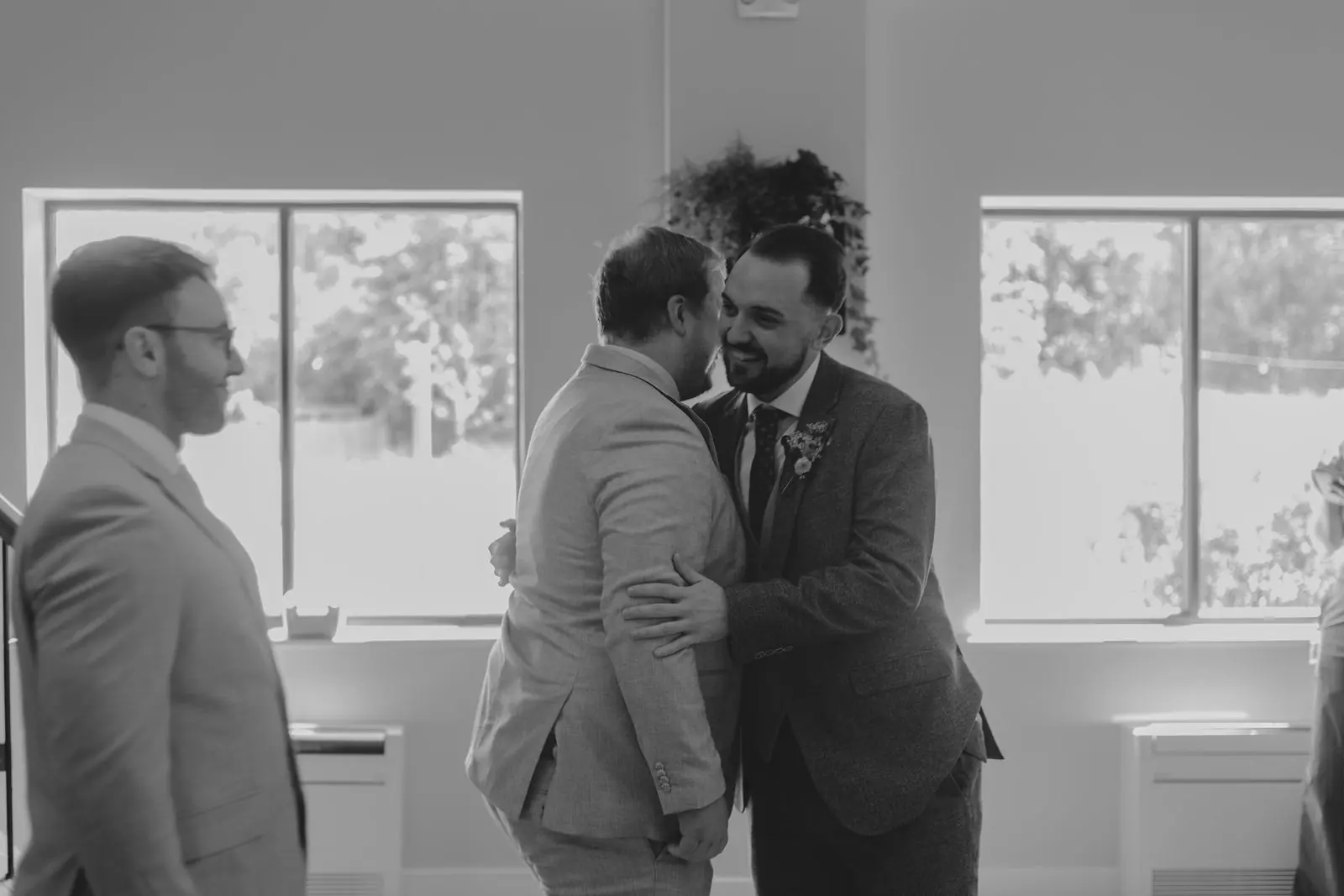 Groom hugging a friend in black and white