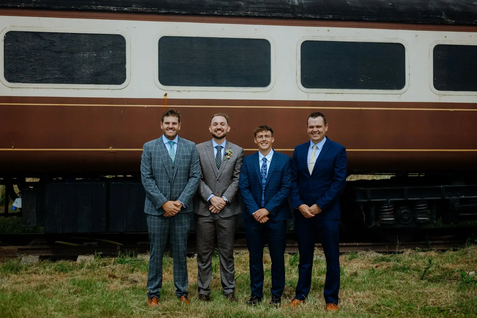 Groomsmen standing in front of a vintage railway carriage