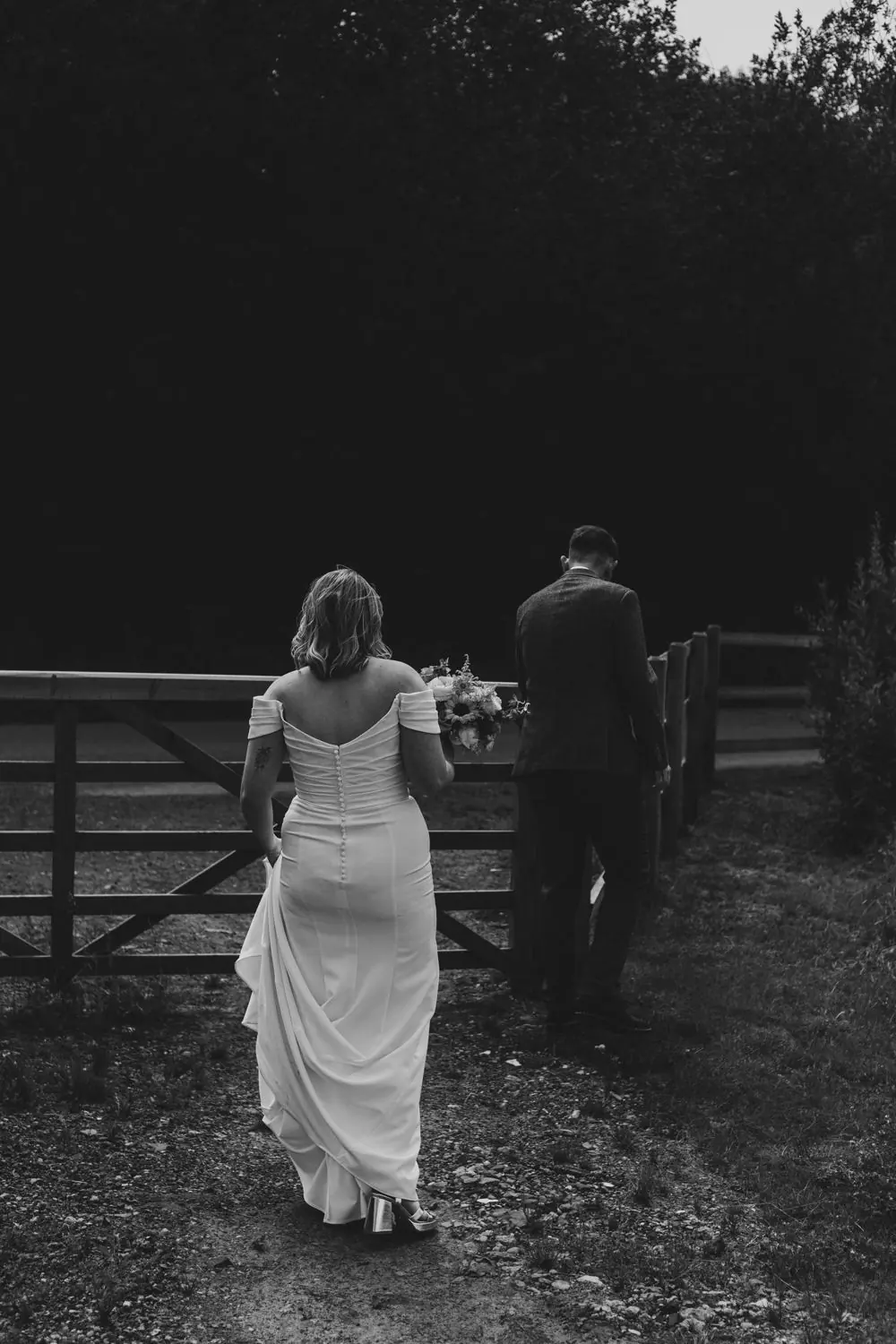 Bride and groom walking through a gate, in black and white