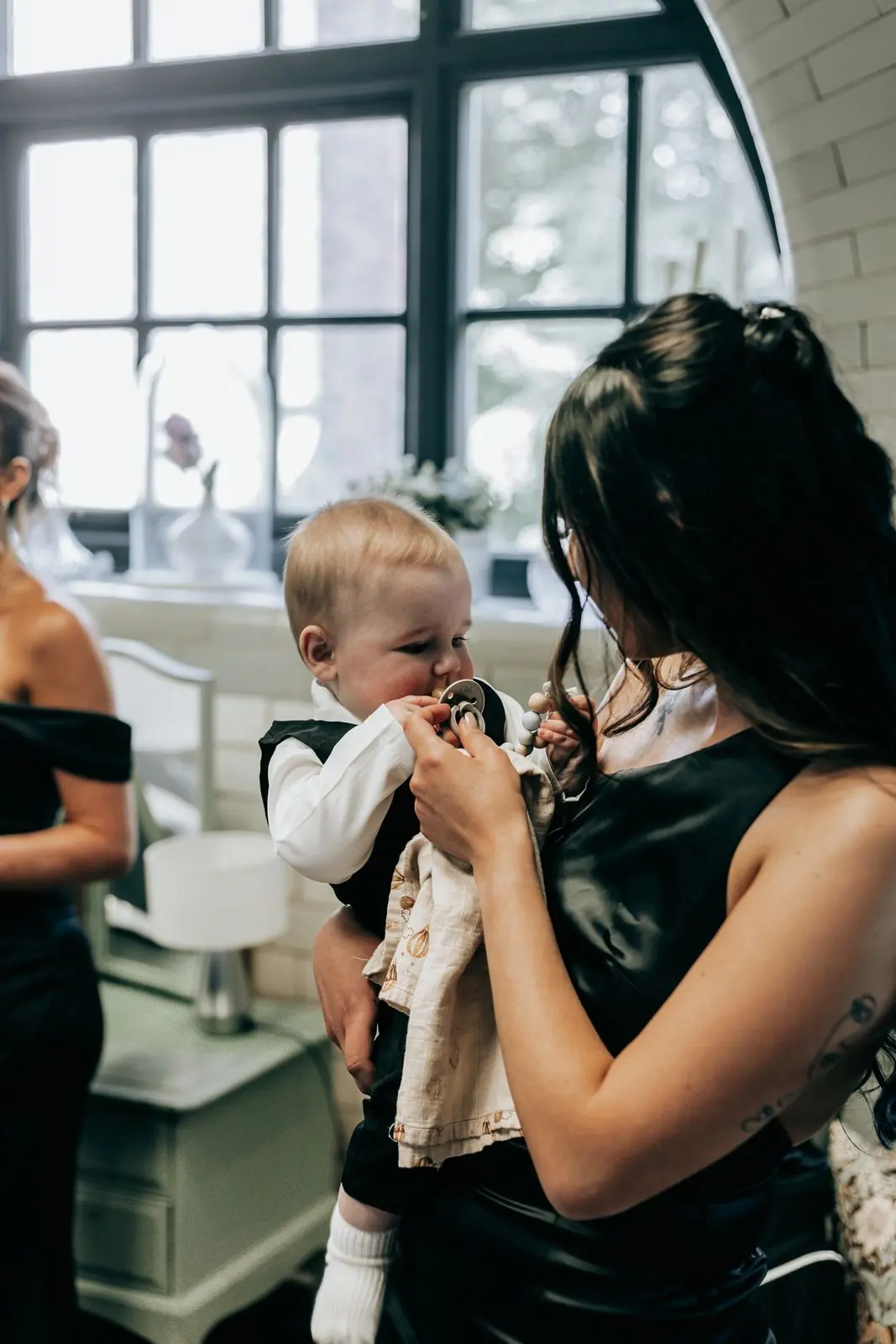 Guest holding a baby by a bright window