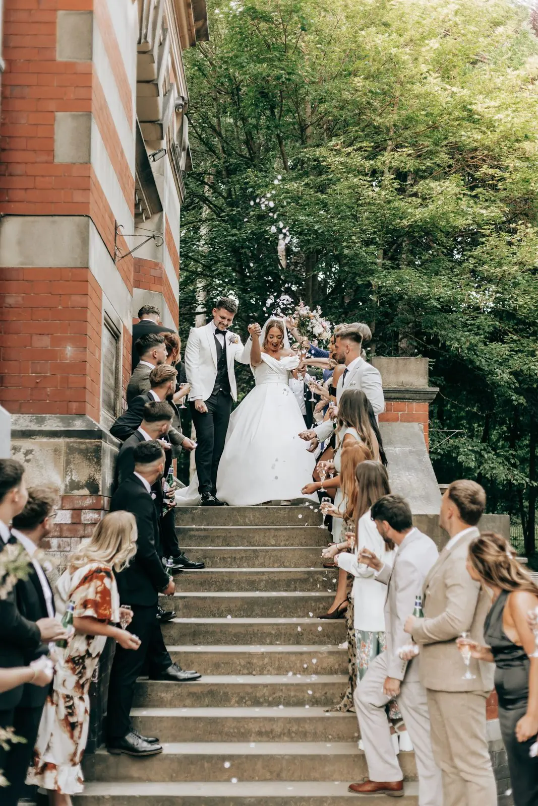 Newlyweds walking down brick steps lined with guests