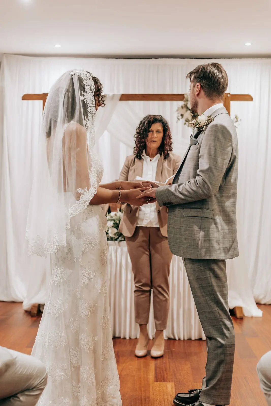 Couple exchanging vows in front of white drapes