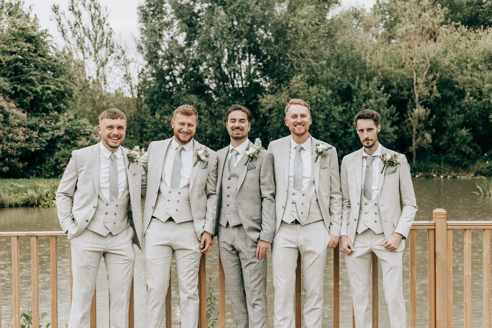 Groom and groomsmen in light grey suits by the lake